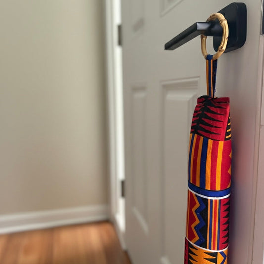 Entryway with a white door, wooden floor, and a red draft stopper hanging from door knob