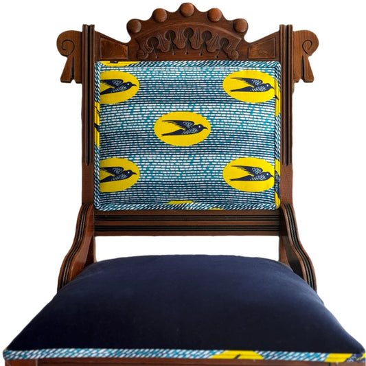 Wooden chair with a blue cushion and yellow Speedbird African wax patterned backrest