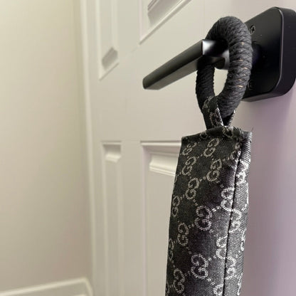 Entryway with a white door, wooden floor, and a black draft stopper hanging from door knob