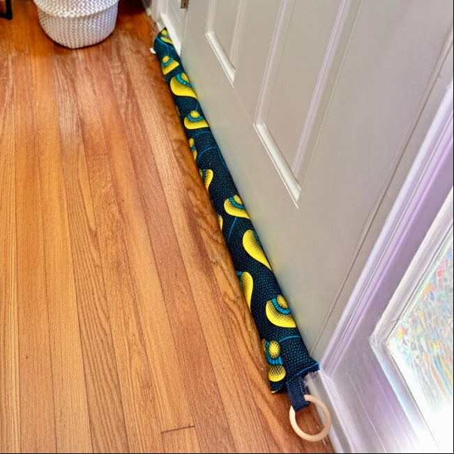Entryway with a white door, wooden floor, and a blue draft stopper hanging from door knob
