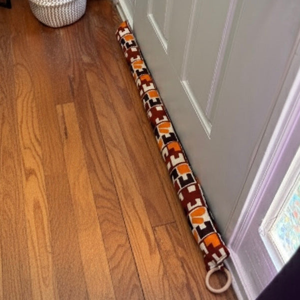 Entryway with a white door, wooden floor and a brown/cream/orange draft stopper