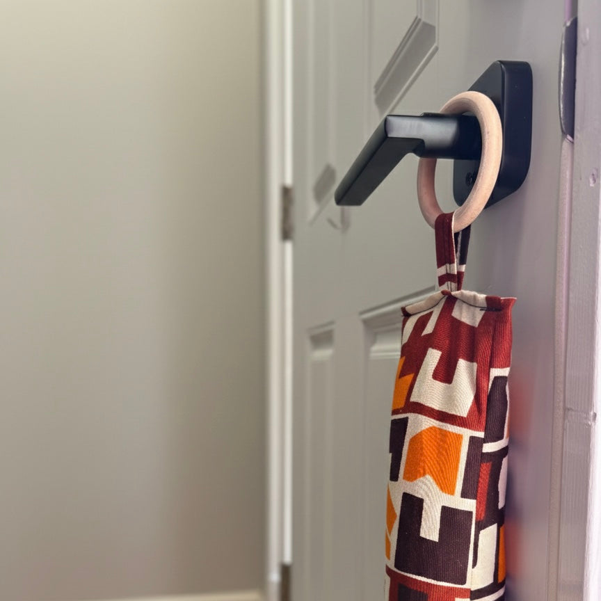 Entryway with a white door, wooden floor, and a brown/cream/orange draft stopper hanging from door knob