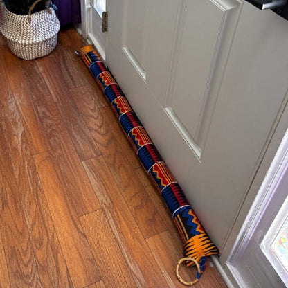 Entryway with a white door, wooden floor and a red/yellow/blue draft stopper