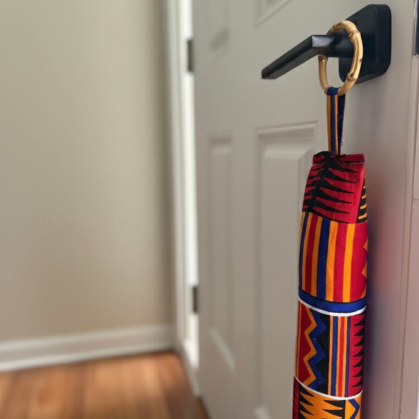 Entryway with a white door, wooden floor, and a red draft stopper hanging from door knob